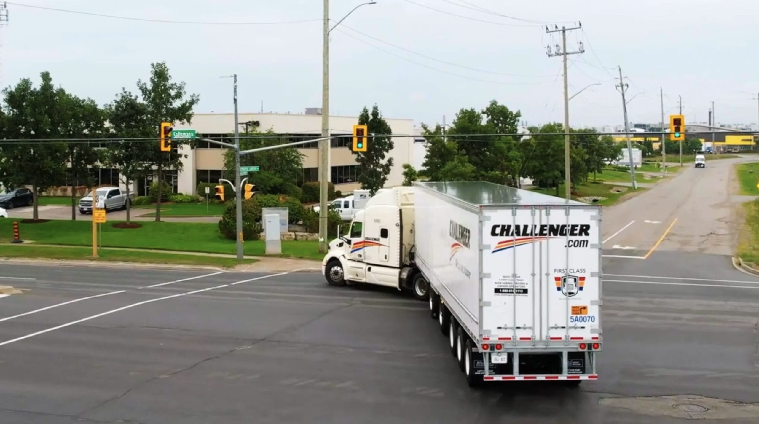 Truck making a turn at an intersection with traffic lights and greenery nearby