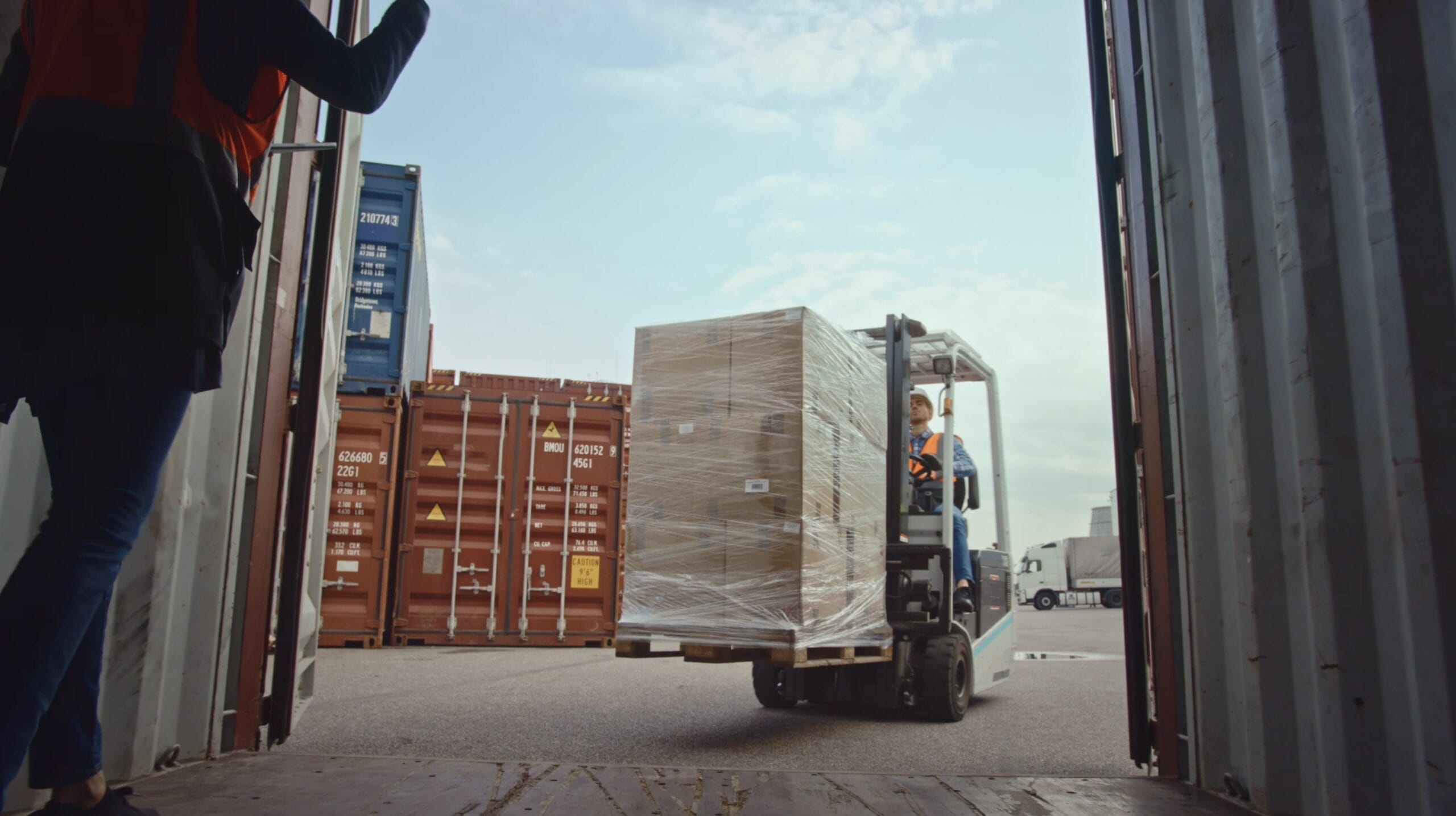 Forklift transporting a pallet of goods out of a shipping container