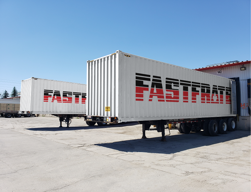 Two shipping containers labeled "FASTFRATE" parked at a loading dock