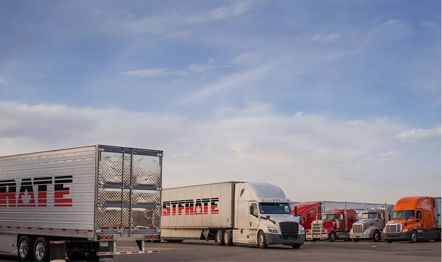 Trucks parked in a lot under a blue sky with clouds