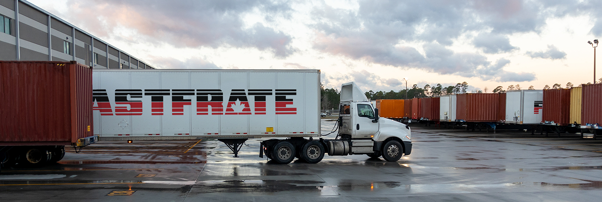 Truck with a large container parked in a loading area with cloudy skies