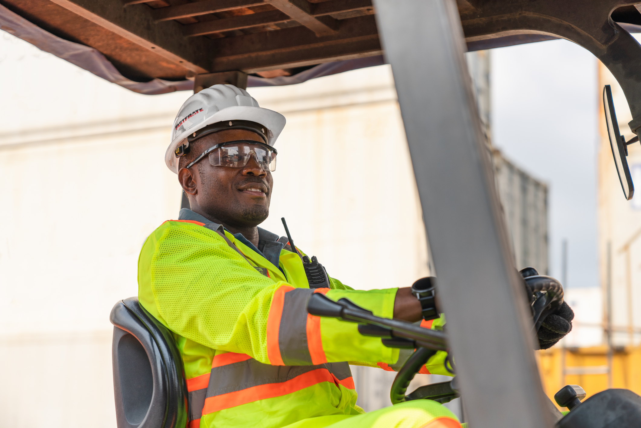 Man in safety gear operating a forklift in a warehouse setting