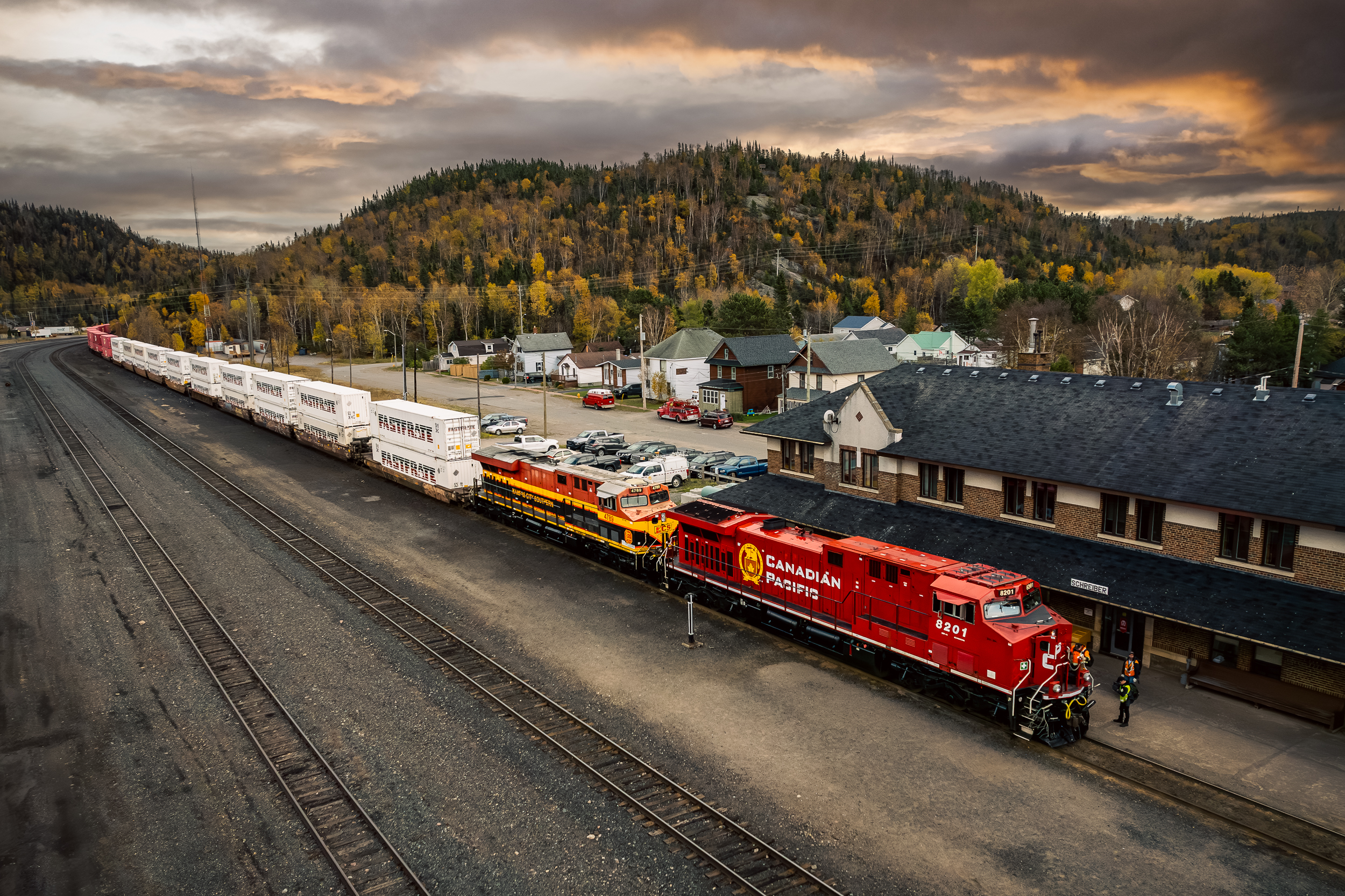 Red and yellow train at a station with mountains in the background