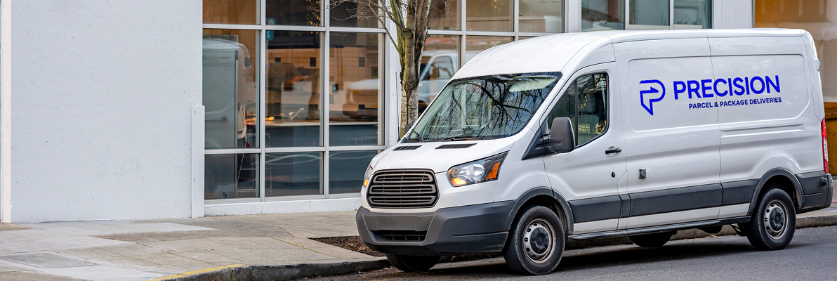 White delivery van parked outside a modern building with large windows