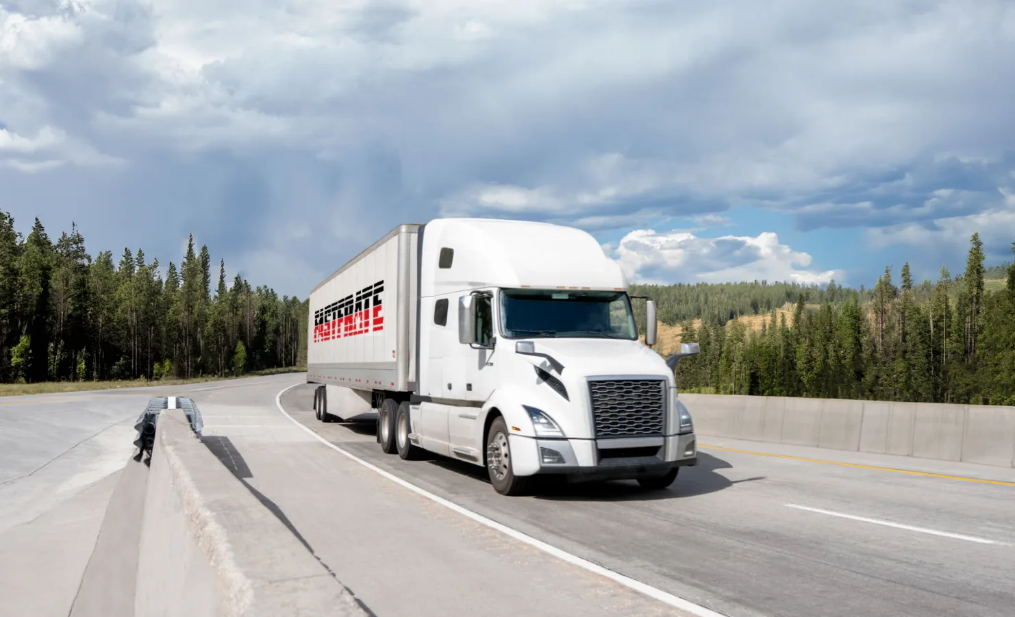 White semi-truck driving on a curved highway surrounded by trees