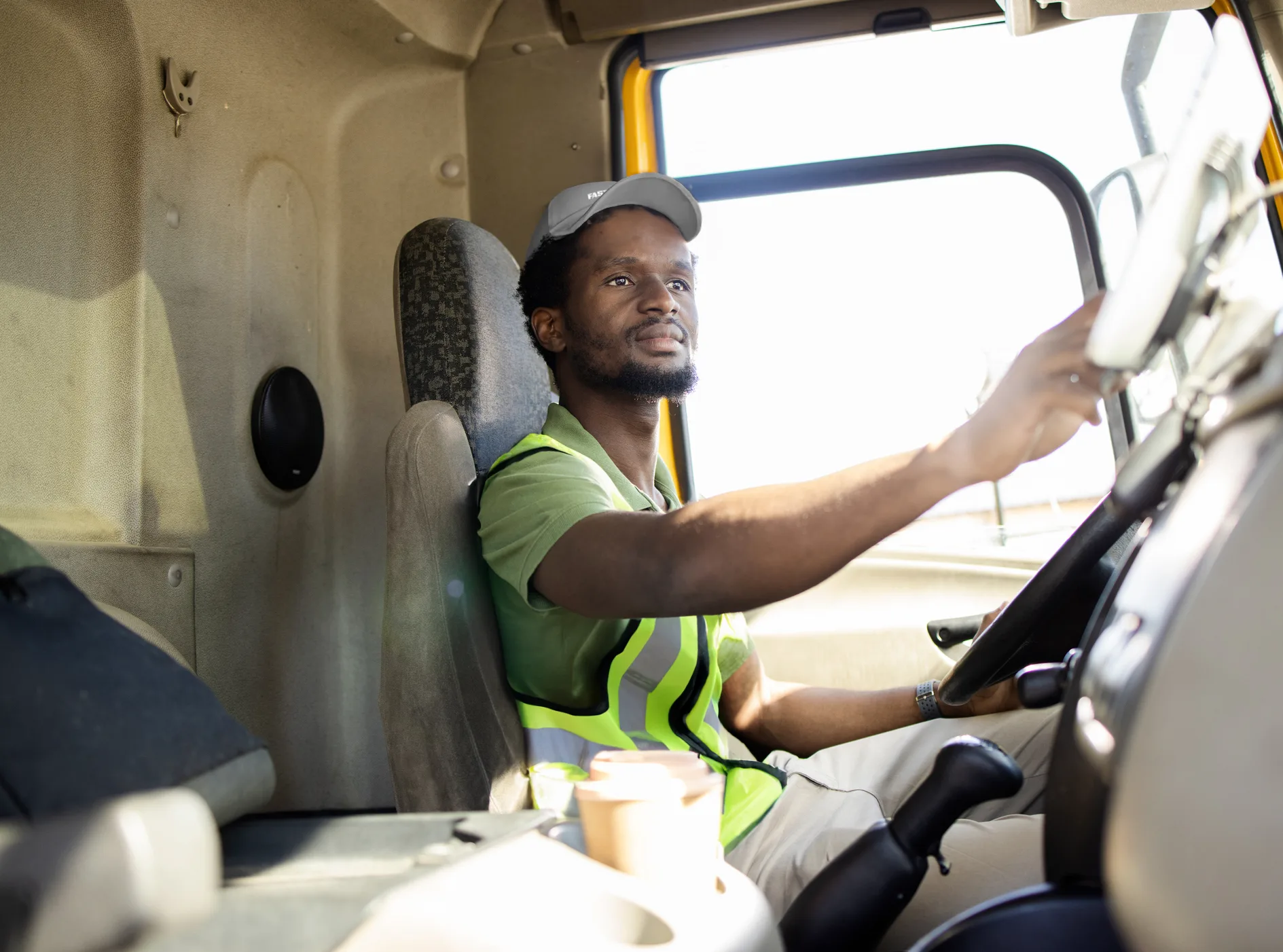 Truck driver wearing a safety vest, focused on steering the vehicle