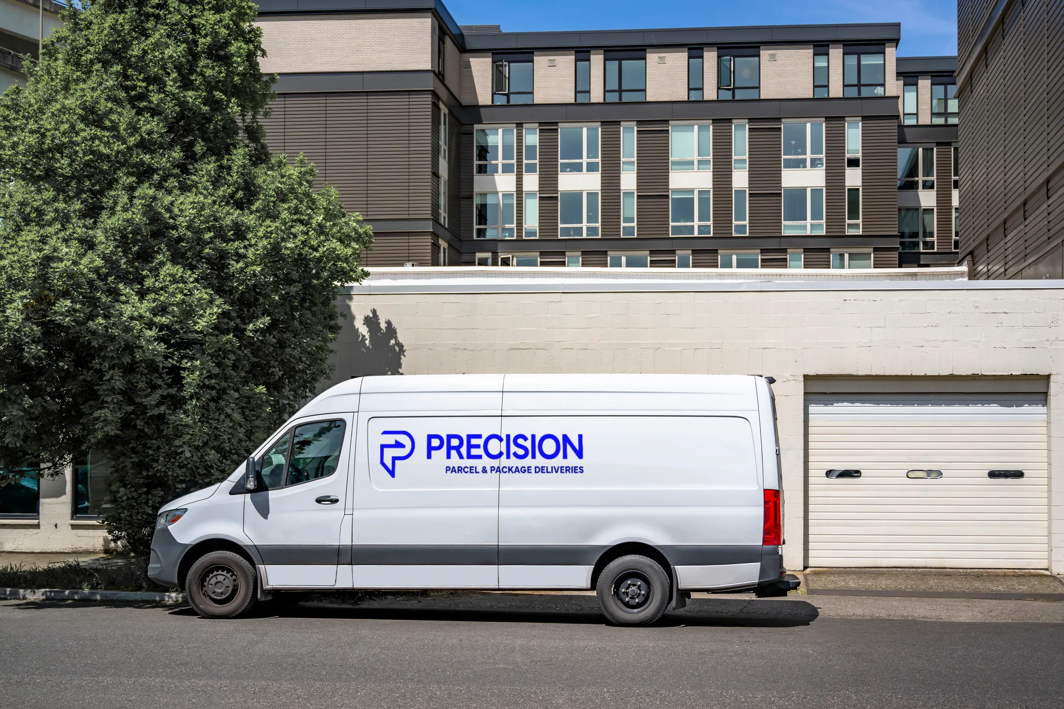 White delivery van with "Precision" logo parked beside a building