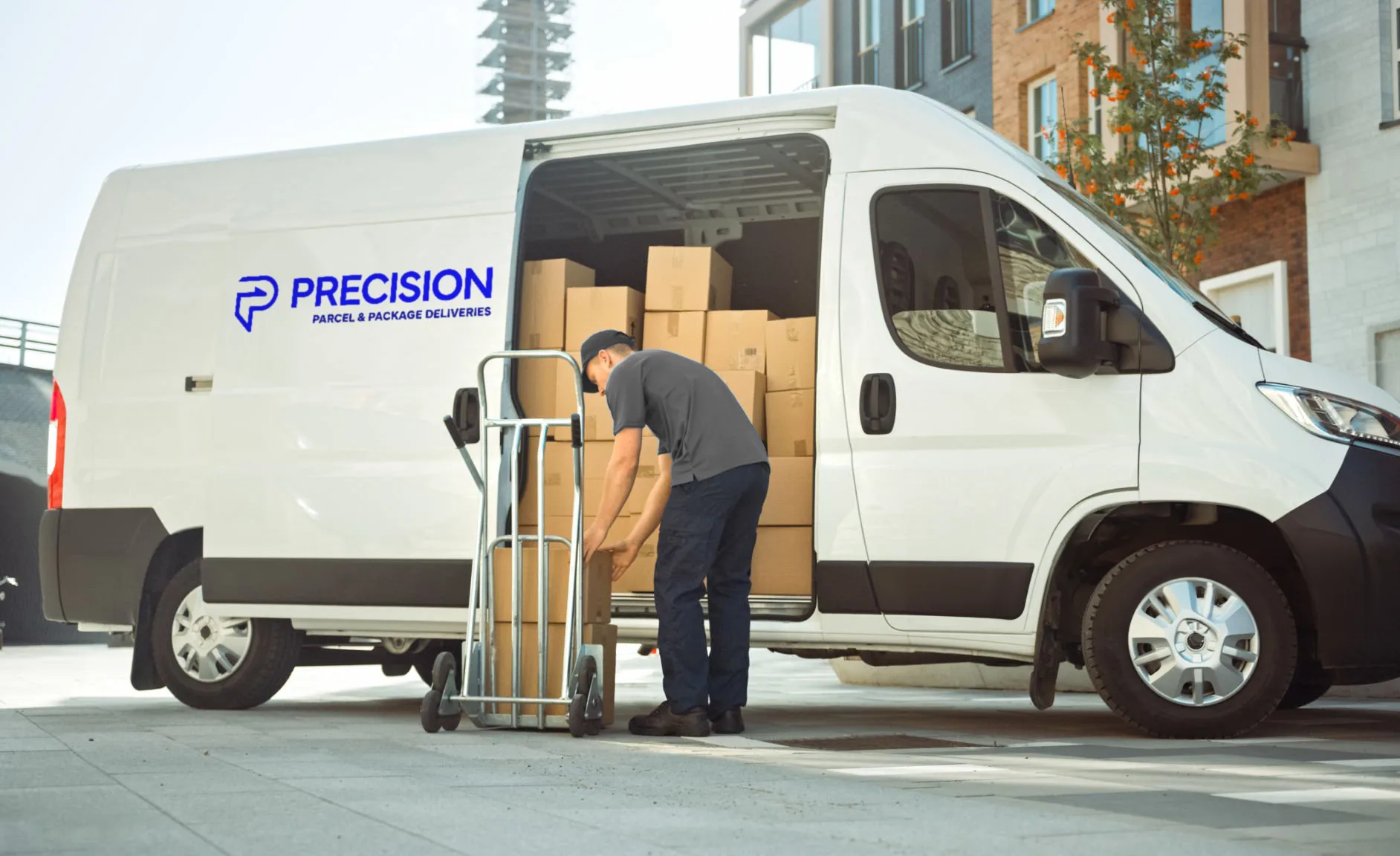 Delivery worker loading boxes into a white van labeled "Precision