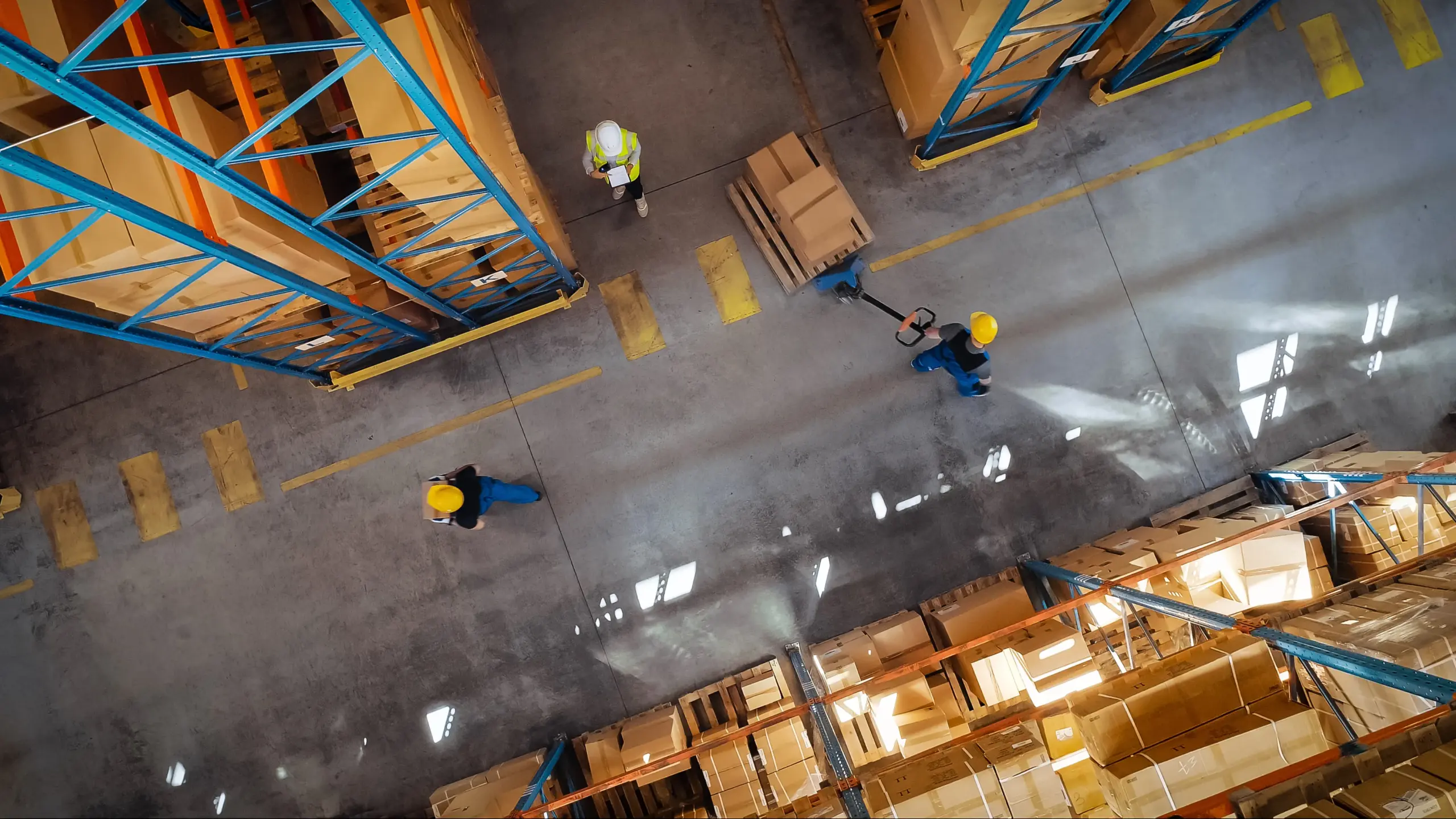 Aerial view of workers in a warehouse with stacked boxes and pallets