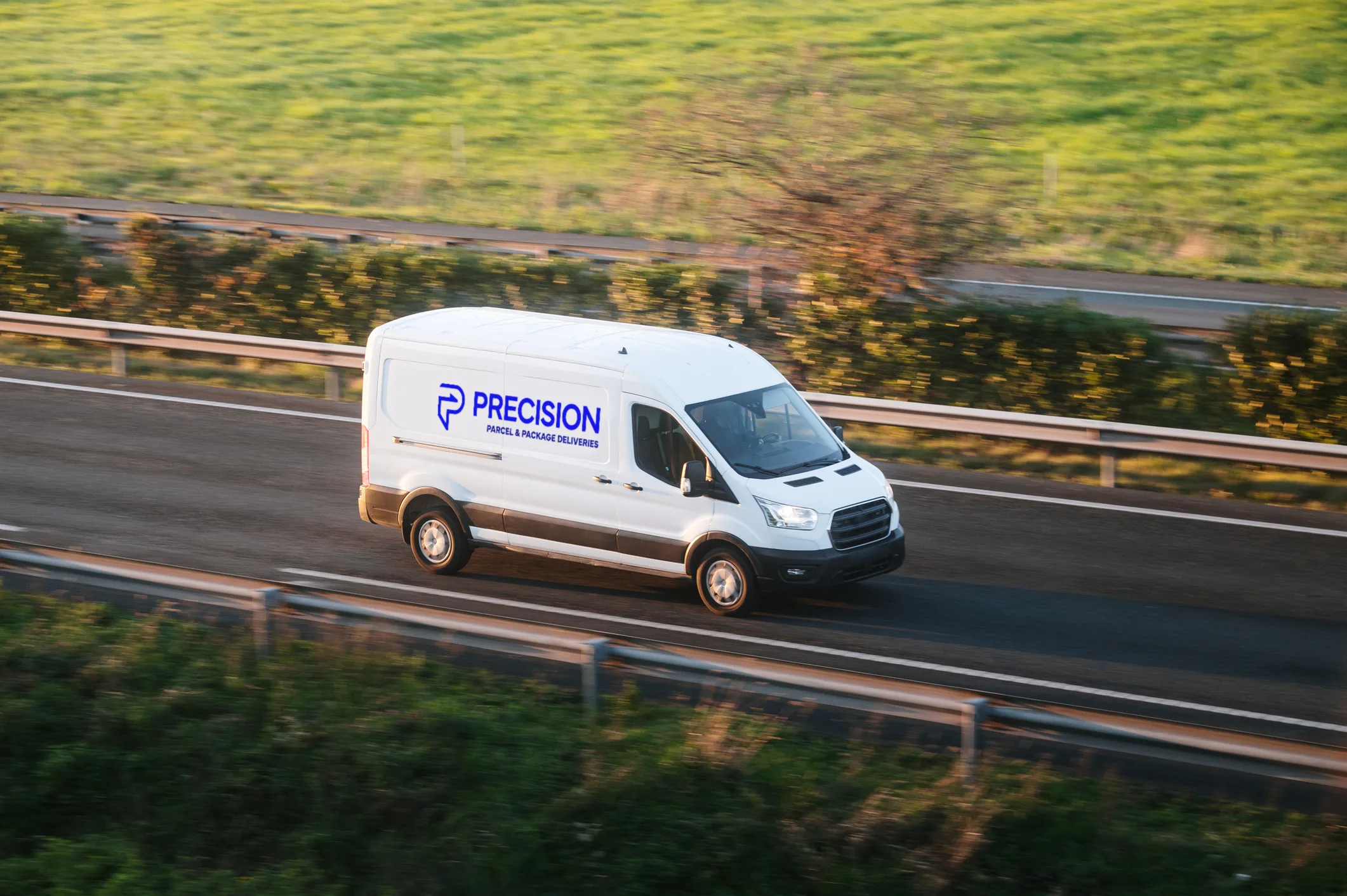 White delivery van with "Precision" logo driving on a highway surrounded by greenery