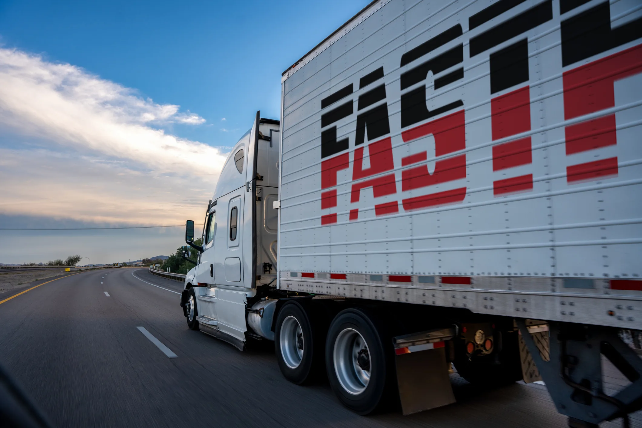 White semi-truck with "FAST" written on the side driving on highway