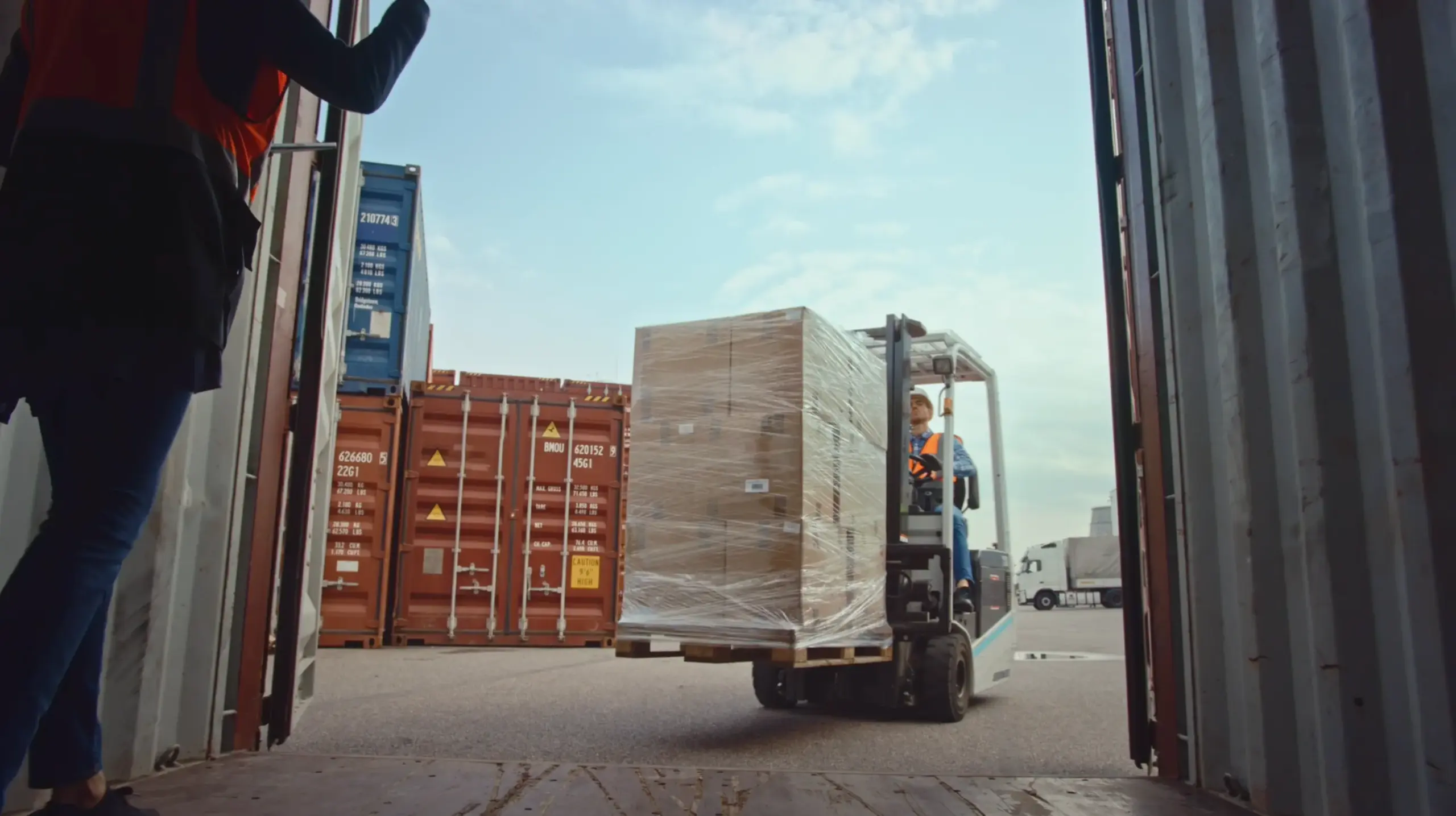 Forklift transporting a pallet outside a shipping container yard