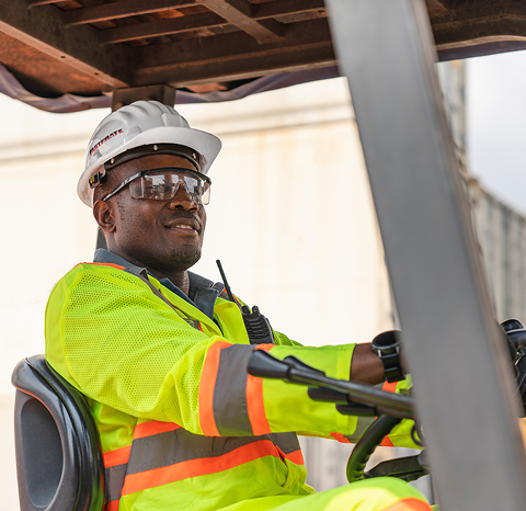 Worker in safety gear operating a forklift in a warehouse setting