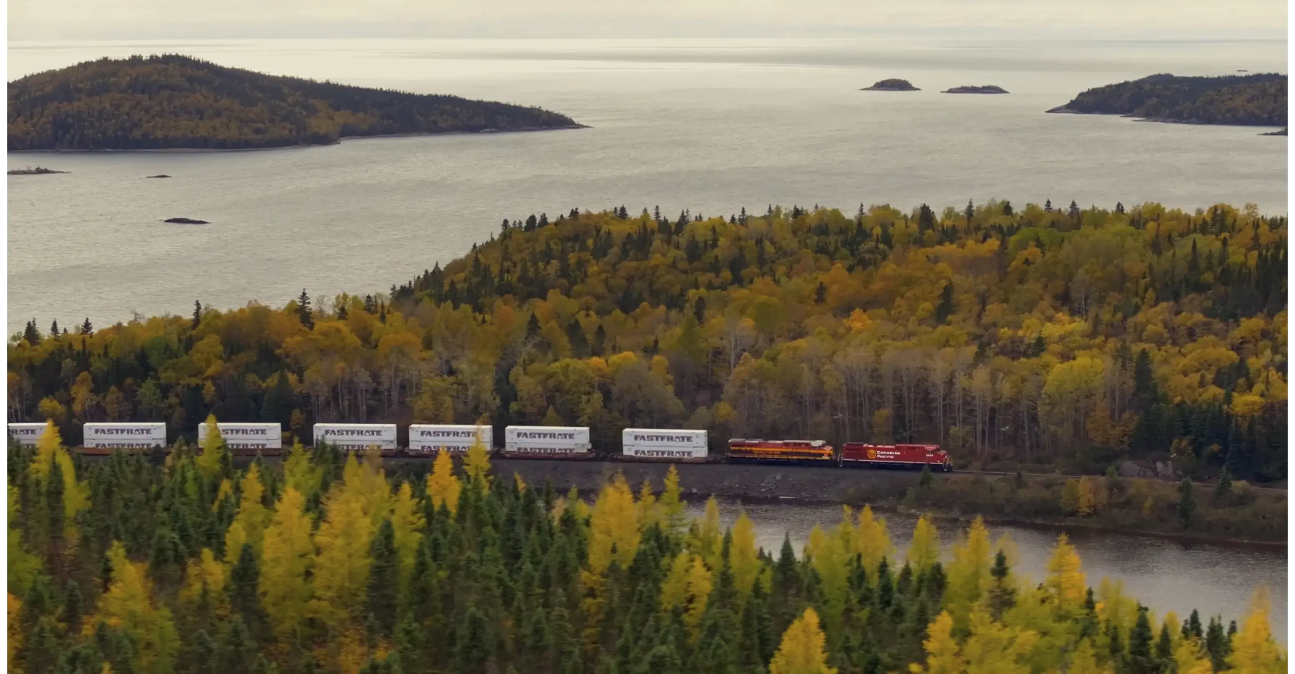 Train traveling along a river surrounded by autumn foliage and islands