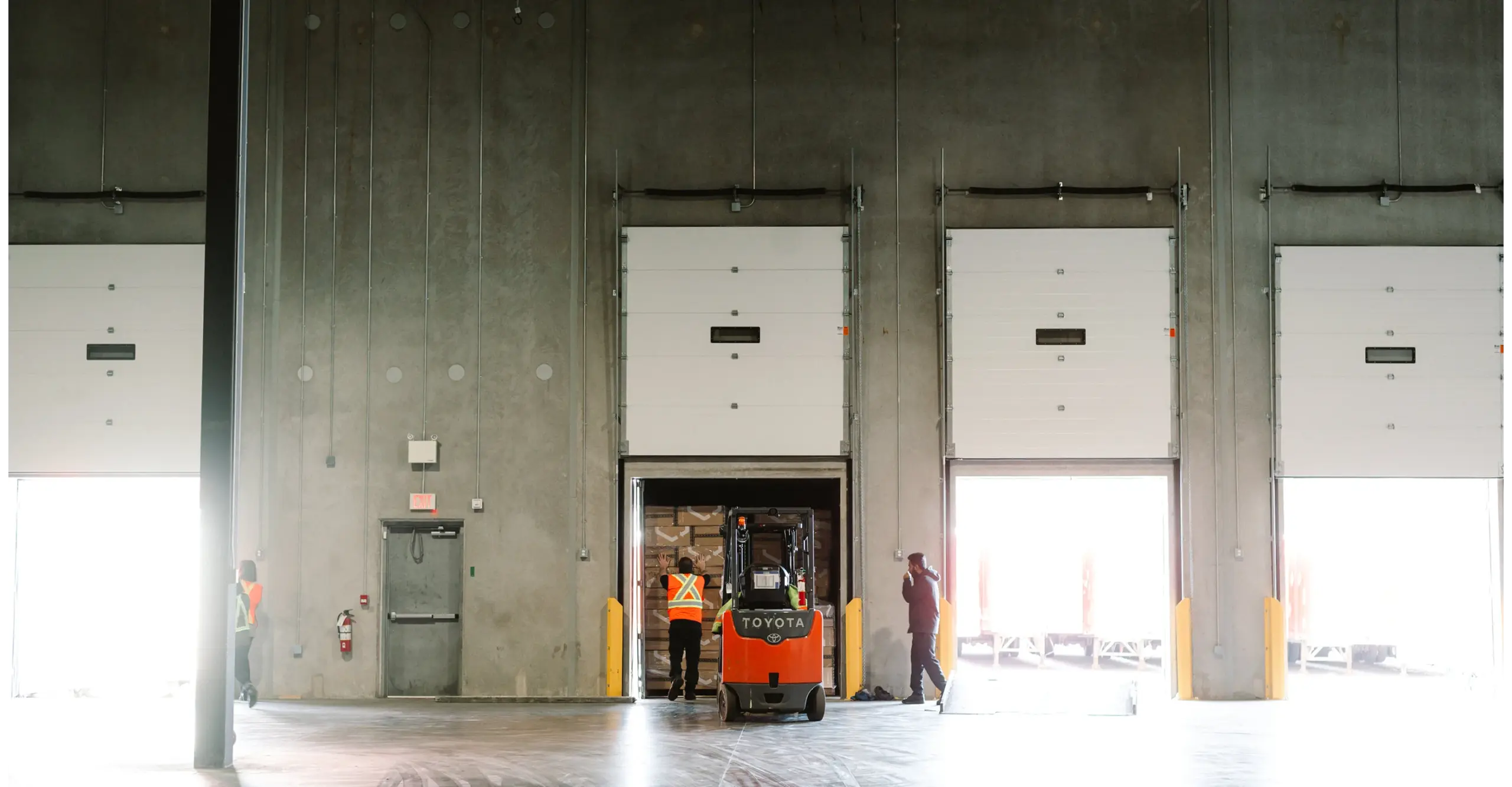 Warehouse interior with loading docks and workers operating a forklift