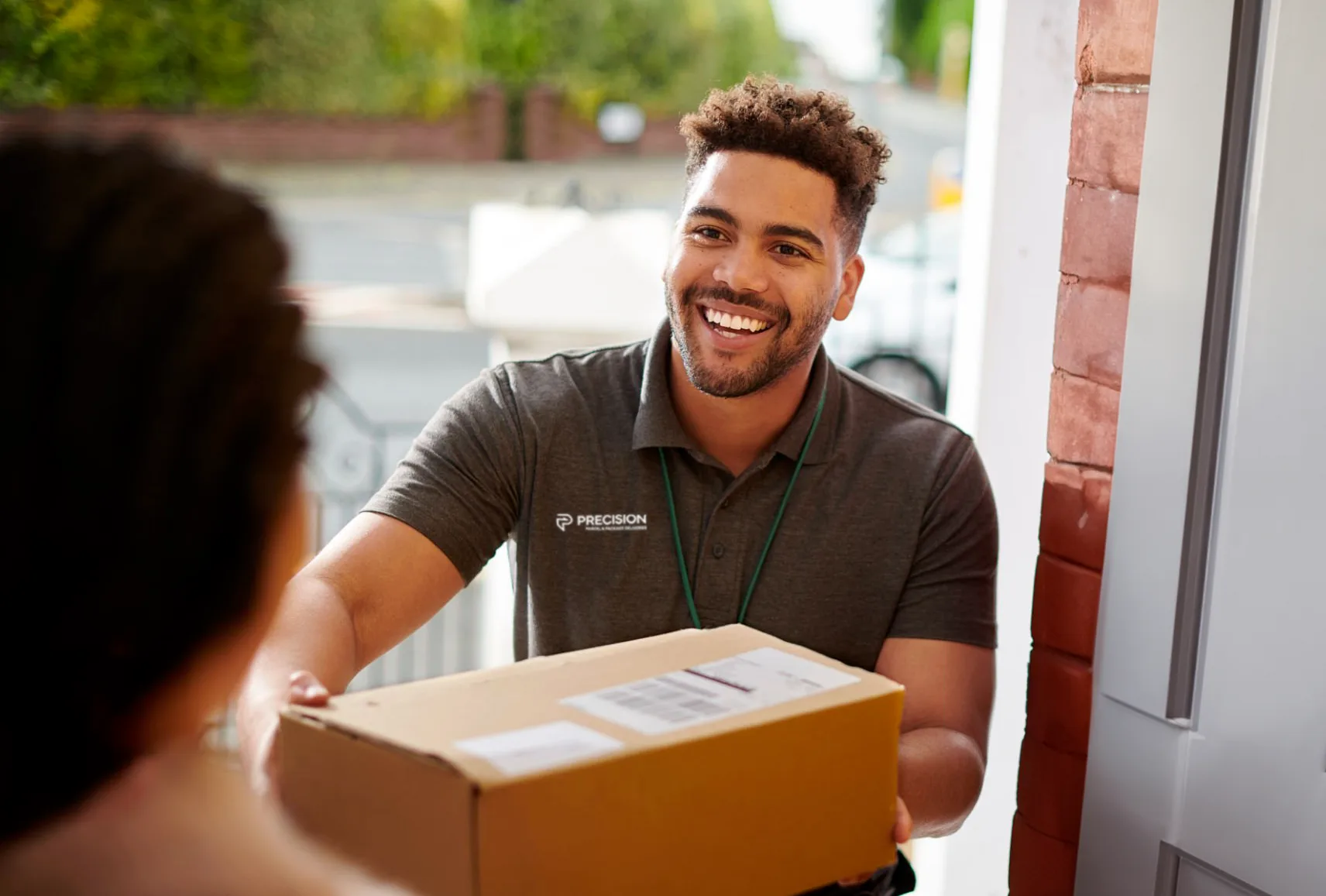Delivery person smiling while handing a package to a customer at the door