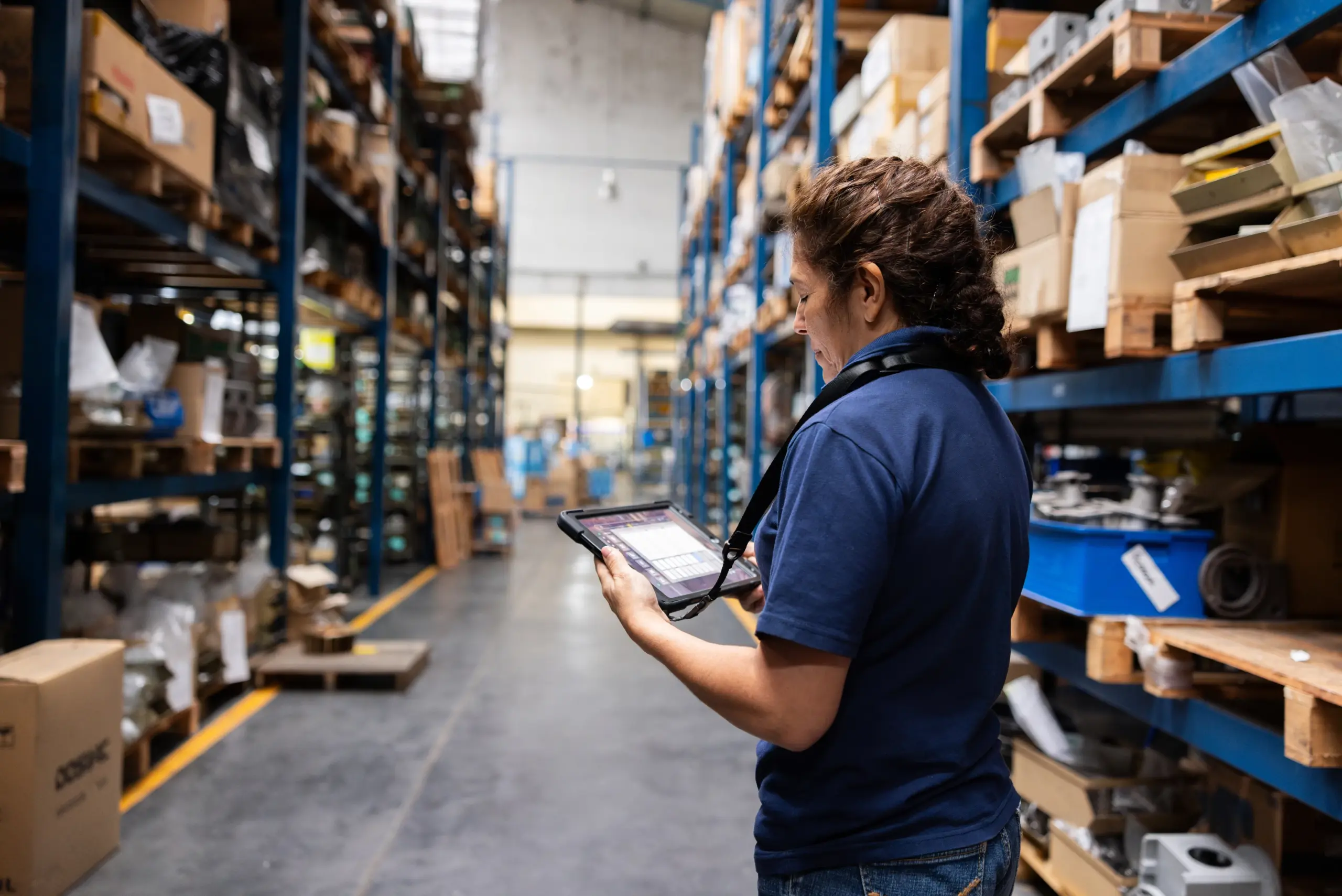 Warehouse worker using a tablet among shelves of inventory