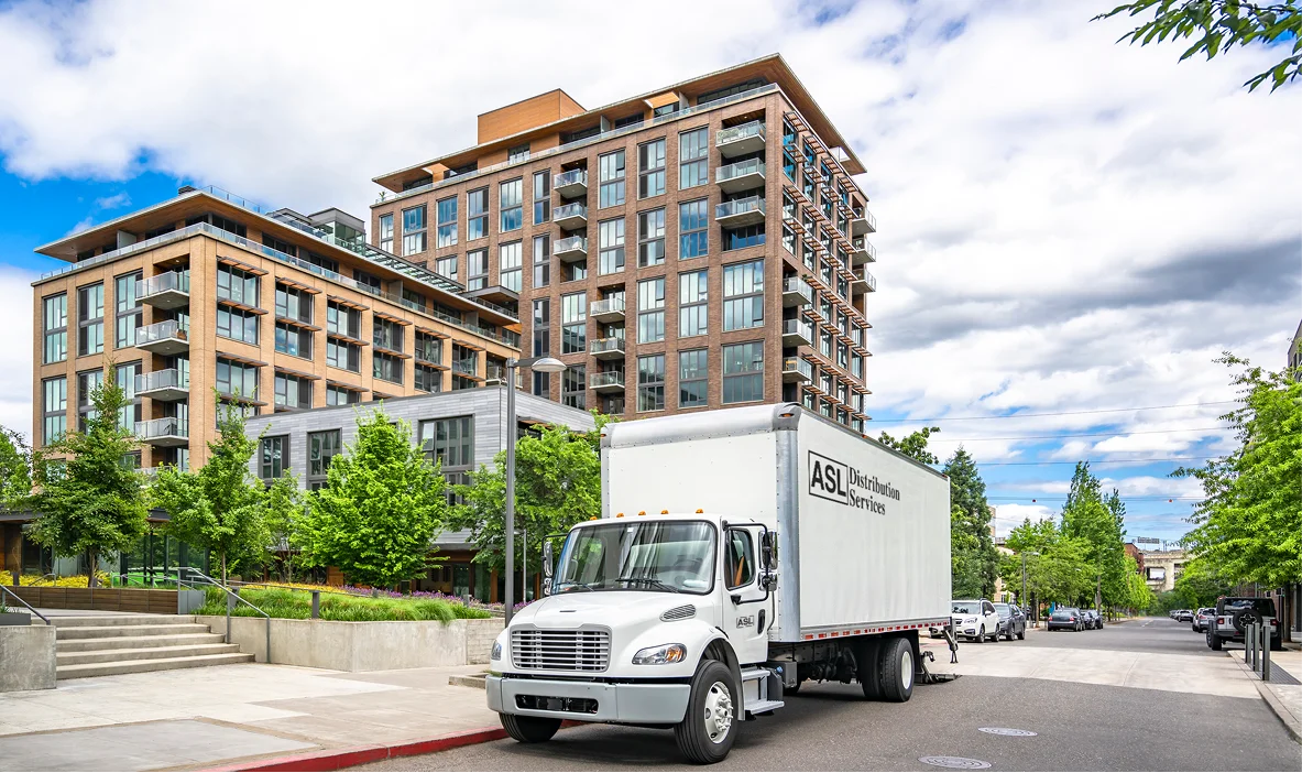 Delivery truck parked on a street near modern apartment buildings